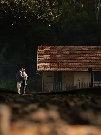 A low-angle shot that uses the texture of the railway tracks to lead the eye to the couple, who share a quiet moment in the distance. This creates a cinematic and story-driven pre-wedding photograph.