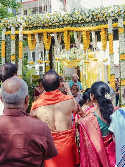 The start of the wedding festivities with a Chapra Puje, where the family gathers under a traditionally decorated floral arch.