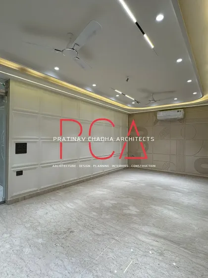 The living area of the Vasant Kunj residence just before handover, showcasing the spacious room with clean wall paneling and modern ceiling design.