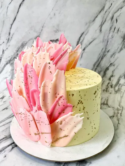 I created this abstract design using colored white chocolate to make feather-like shards. The shades of pink and the splatter of gold dust give it a modern, artistic feel.