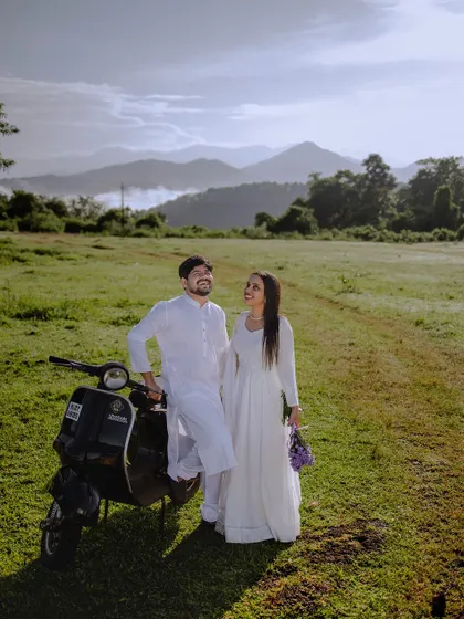 A wide shot capturing the couple, the scooter, and the magnificent mountain range. This is a great example of a destination shoot near Sakleshpur.