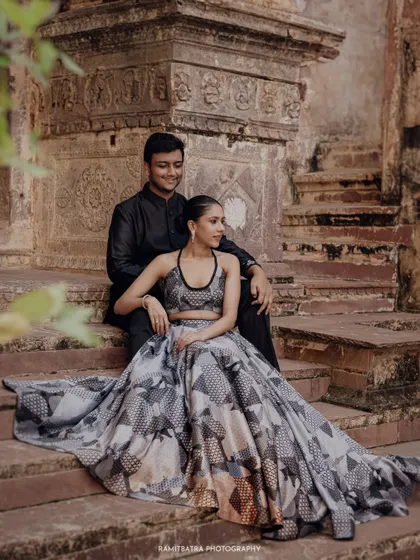 The couple sits on the ancient stone steps of Fort Barwara, a blend of modern fashion and historic texture.