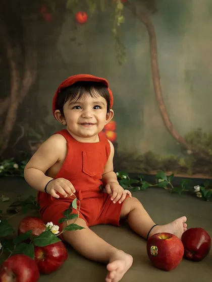 A happy apple-picker. This little boy's smile is as bright and cheerful as his red outfit.
