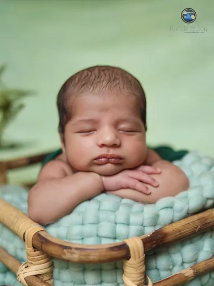 The perfect "tummy time" pose. This close-up shot highlights the baby's adorable pout and chubby cheeks as he rests his head on his arms in a woven basket.