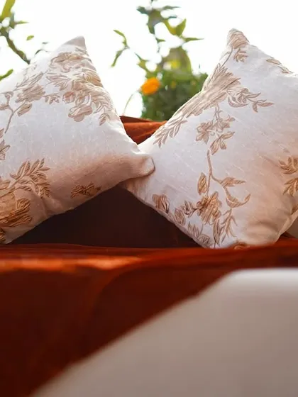 Elegant cushions with intricate floral embroidery, adding a touch of luxury to the rustic-themed outdoor seating area.