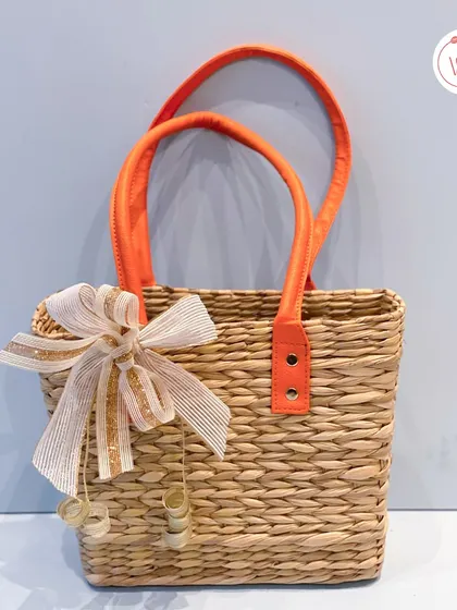 A chic and sustainable jute basket with bright orange handles, perfect for a vibrant Mehendi or Haldi welcome hamper.