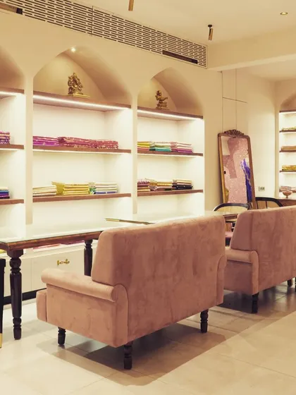 A comfortable seating lounge area within the retail space. The plush sofas and back-lit shelving provide a relaxed space for customers, enhancing the luxury shopping experience.
