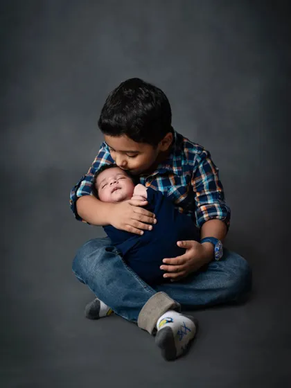 A tender kiss for the new baby. Sibling photos with a newborn are some of the most special memories we capture.