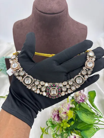 A close-up look at the fine detailing on this Moissanite and Kundan choker. The combination of large uncut stones with a ruby and emerald green center makes it a classic and highly sought-after design.