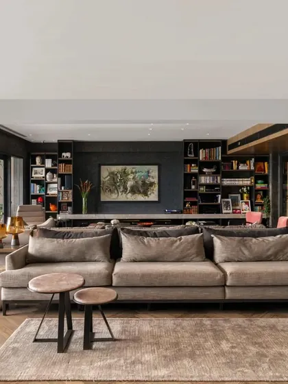 In the Caitriona apartment, the living room is designed for comfort and function. A large, plush sofa is paired with an eclectic mix of coffee tables and ottomans, while the custom TV wall integrates storage and technology seamlessly into the design.