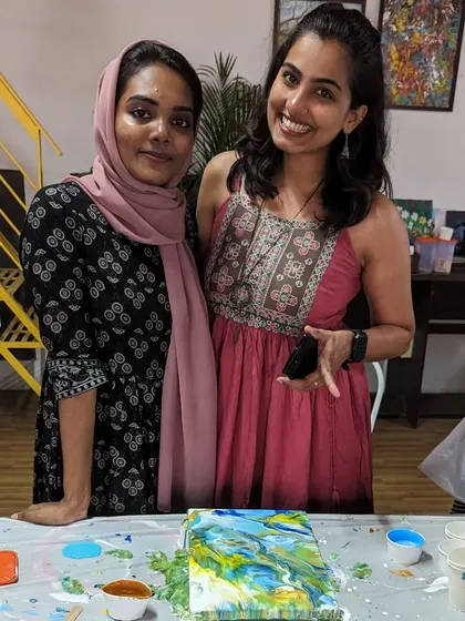 Two friends enjoying a pour painting session. The joy and laughter are just as important as the art itself.