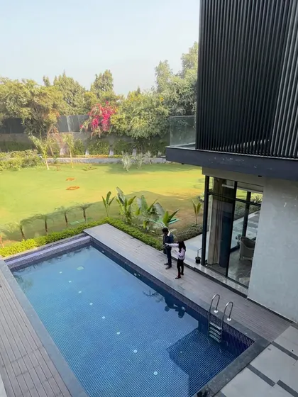 An aerial view of the pool at the Modern Canopy House shows our co-founders standing on the wooden deck. This perspective highlights how the pool, deck, and lawn are designed as interconnected zones for leisure and socializing.