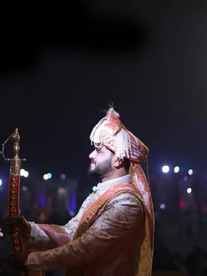 The groom's entrance, holding a ceremonial sword (kirpan), captured with dramatic lighting.