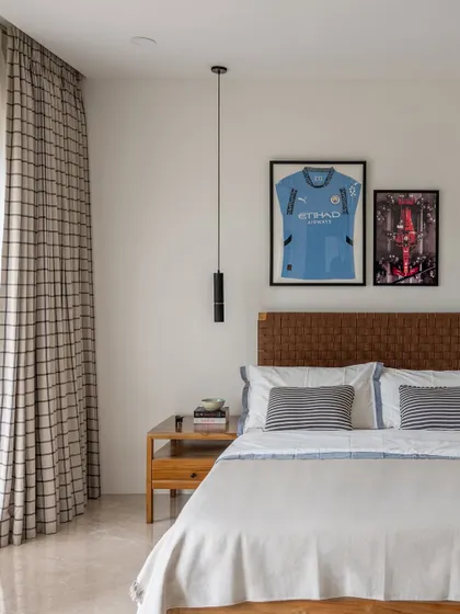 We design bedrooms to reflect the personality of their occupants. This room features a woven leather headboard and framed sports memorabilia, creating a space that is both stylish and deeply personal.