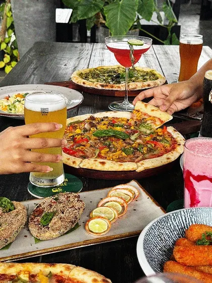 A feast for friends, featuring pizzas, appetizers, beers, and milkshakes.