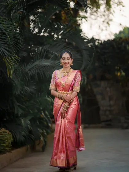 A full-length portrait of the bride, showcasing the elegance of her traditional silk saree and gold jewelry.