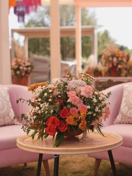 A beautiful floral arrangement on a side table, with soft pink sofas in the background, creating a romantic and relaxed vibe.