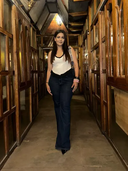 A simple and classic outfit for a night out. A white tank top with black trim paired with high-waisted flared jeans and heels.