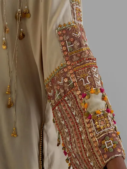 A detailed view of a sleeve adorned with intricate patchwork, tassels, and mirror work, a celebration of traditional crafts.