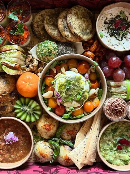 A top down view of one of my vibrant grazing hampers, showcasing the rich colors and textures. You can see the creamy burrata, fresh fruits, savory dips, and even sweet treats like cookies, all artfully arranged.