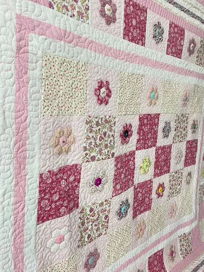 A detailed shot of a hexagon quilt, where you can see the 3D-effect of the appliqué flowers and the intricate background quilting.
