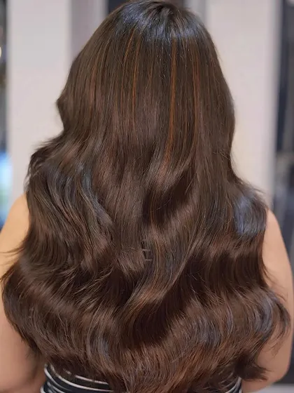 The back view of this long brunette style, showing the subtle copper highlights woven through the hair for a warm, rich effect.