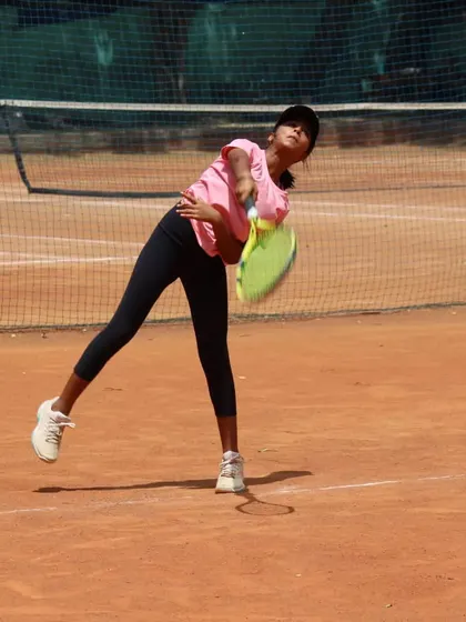 A junior player practicing her service motion. Repetition is the mother of skill.