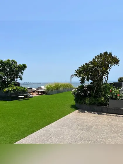 An expansive view across a rooftop garden overlooking the Mumbai sea link. I placed mature trees in large planters to anchor the space and create a sense of scale against the vastness of the sky and water.
