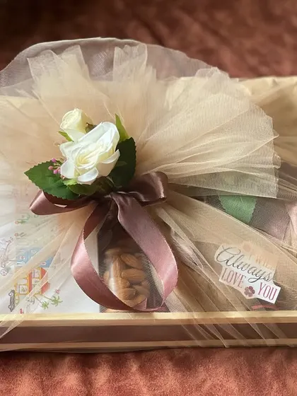 The rustic Rakhi hamper, now fully wrapped in beige net with a white rose. The wrapping enhances the gift's elegance while keeping the contents secure.