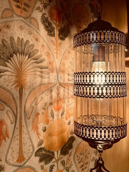 We decorated this wall with a beautiful Indian-themed wallpaper from Nilaya. Paired with a classic glass and metal lantern, it creates a warm, inviting, and culturally rich corner.