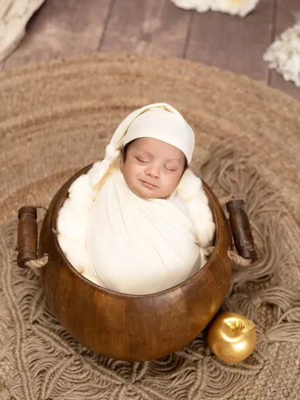 A peaceful smile on a sleeping newborn's face. Tucked into a wooden bowl with a golden apple, this portrait is simple, warm, and utterly precious.