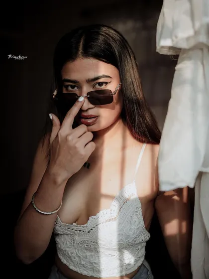 A powerful portrait where the model interacts with her sunglasses, framed by dramatic window light. This adds a layer of attitude and style.