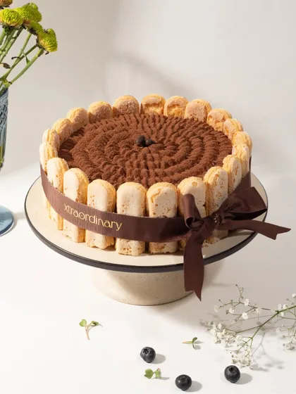 A full view of our Tiramisu cake, wrapped with our signature ribbon. It's an elegant dessert for any dinner party or celebration.