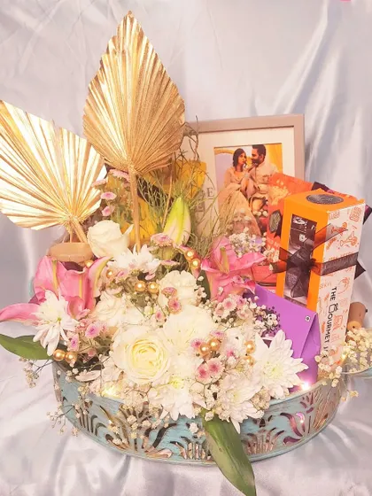 Another angle of our fresh floral gift hamper. The combination of white and pink flowers, golden palm leaves, and a personal photo makes this a stunning centerpiece and a heartfelt present.