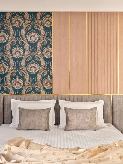 The parents' bedroom in 'Muditā' is warm and inviting, with wooden tones, brass inlays, and a rich damask wallpaper panel. The design focuses on creating a cozy and elegant atmosphere.