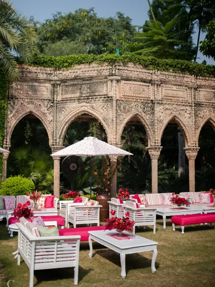The garden setting for the 'Gulnar' Mehendi, with comfortable lounge seating and vibrant cushions against the backdrop of the ancestral home's architecture.