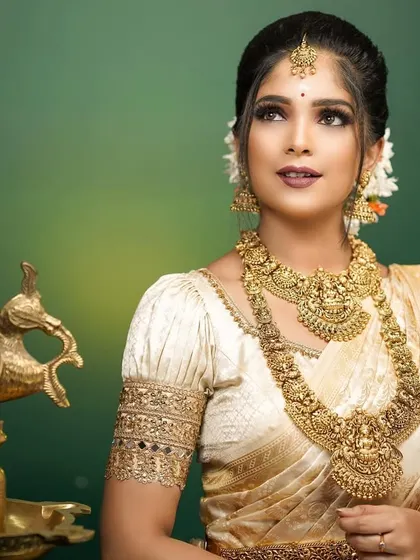 A beautiful portrait capturing the serene and graceful spirit of Onam. The all-gold jewelry perfectly complements the cream and gold saree.