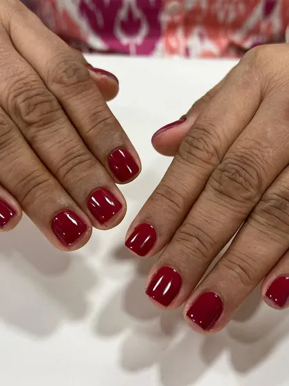 A classic red gel polish on short, square nails. This timeless color is perfect for any occasion and always looks sophisticated.