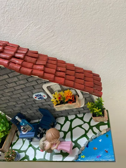 An overhead view showing the hand-laid terracotta roof tiles on the miniature house. Each tile is individually crafted and placed to create a realistic, rustic look.