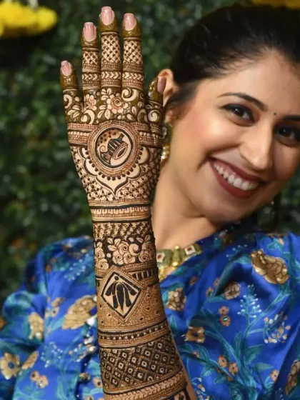 The lovely bride showing off her full-arm mehndi. This view highlights how the intricate patterns on the palm and forearm come together to create a complete and stunning bridal look.