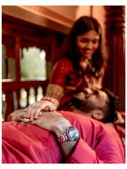 A creative, intimate shot focusing on the groom's watch as he rests his head on his fiancée's lap, capturing a moment of peace and connection.