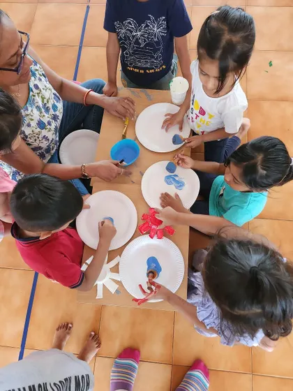 An overhead view of children painting together. Art activities encourage social interaction as they share materials and see each other's work.