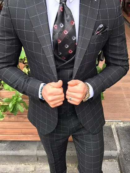 A charcoal grey three-piece suit with a subtle windowpane pattern. The patterned tie adds a touch of personality to this classic formal look.
