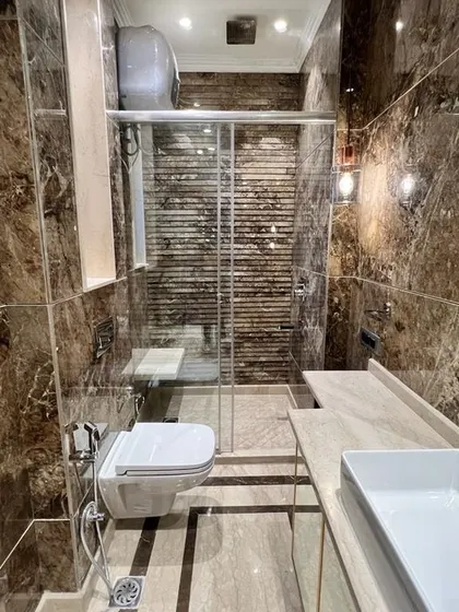 Another view of this stunning bathroom at C-257. The rich brown marble, glass shower partition, and modern vanity create a space that feels like a five-star hotel.
