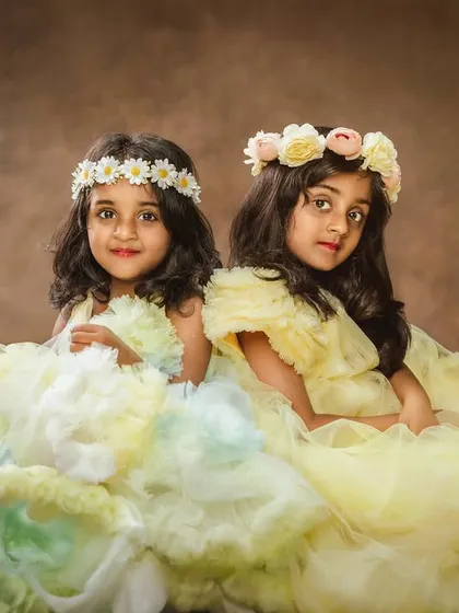 Two sisters in beautiful, flowing yellow gowns and flower crowns. They look like little fairies in this enchanting studio portrait.