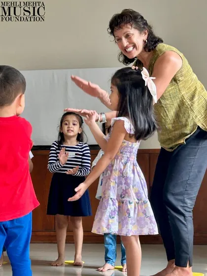 A teacher and students interact during a musical game. These playful exchanges build rapport and create a positive, encouraging learning atmosphere.