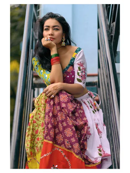 A colorful and energetic portrait of a model in a folk-inspired outfit. The image is full of joy and movement.