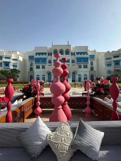 A glimpse of the Salwa Beach celebrations in Doha. The lounge seating, with its modern black-and-white cushions, looks out onto a courtyard filled with unique pink sculptural art.