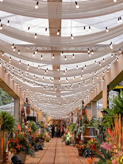The draped fabric and string light canopy over the entrance walkway, creating a beautiful and inviting passage into the main event area.