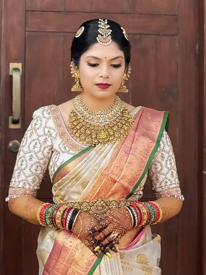 This image captures the regal essence of a South Indian bride. The focus is on the magnificent gold jewelry and the rich silk saree, with makeup that enhances her features with a classic red lip.